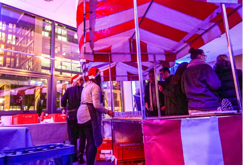 Glühweinstand auf mobilem Weihnachtsmarkt in Frankfurt – Mitarbeiter genießen heißen Punsch und Stimmung