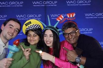 Internationales Team nutzt Fotobox mit Props auf Messestand mit Corporate Branding.