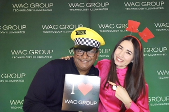 Messebesucher posiert mit Props vor gebrandeter Fotobox Wand.