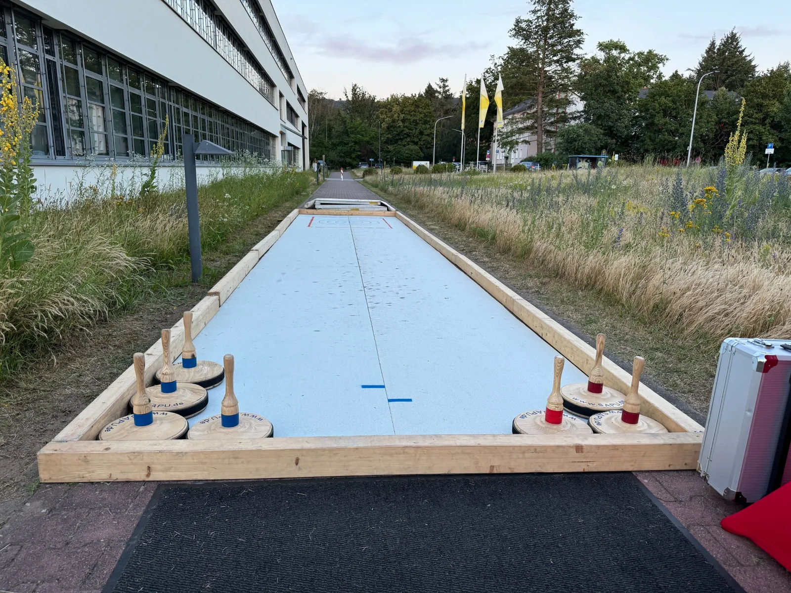 Mobile Eisstockbahn mit Holzrahmen und Eisstöcken im Außenbereich