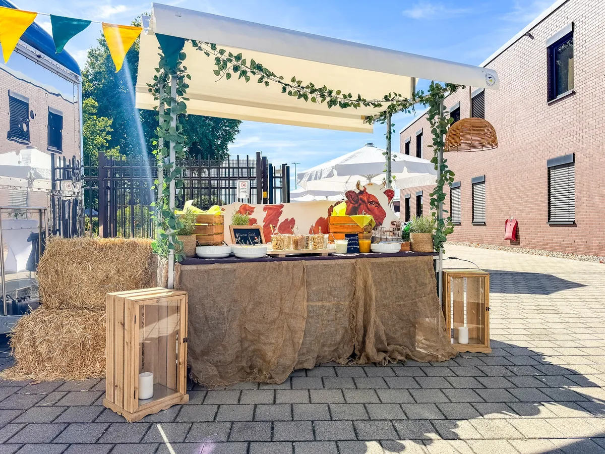 Sommerlicher Themenstand mit Holz, Strohballen und Pflanzen bei John Deere