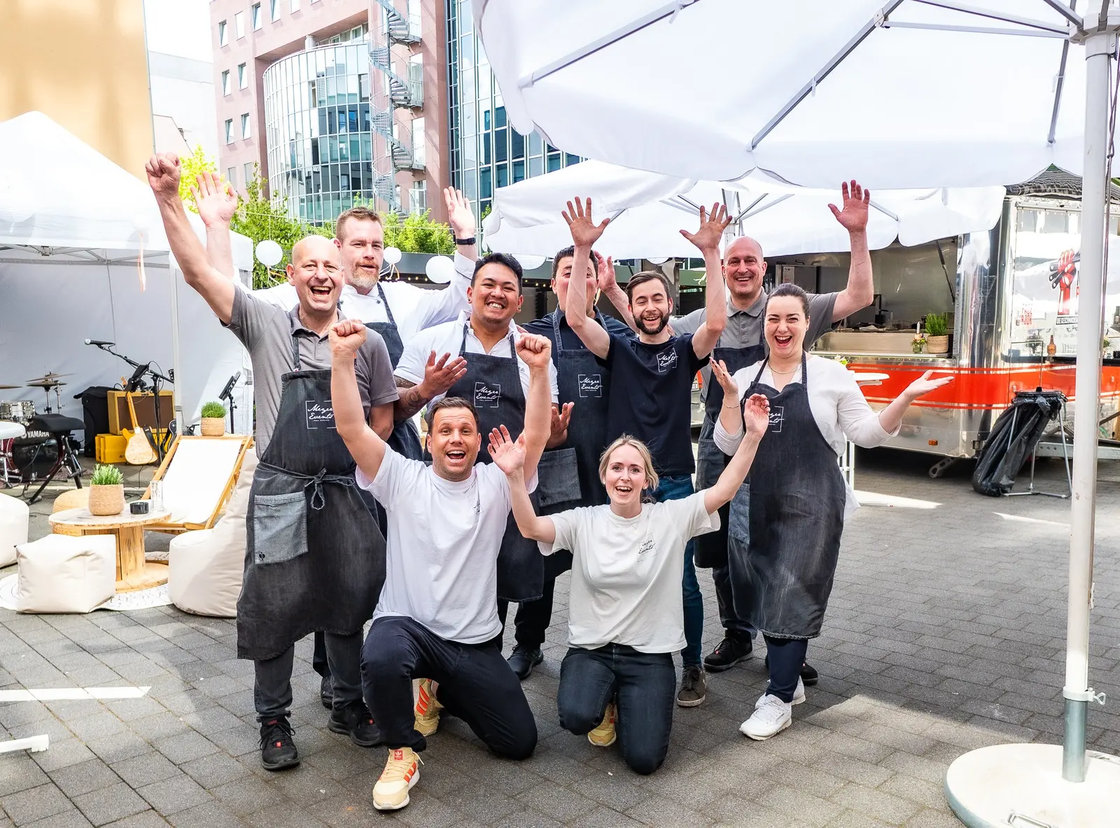 Das Meyer-Events-Team winkt lachend auf einem Veranstaltungsgelände