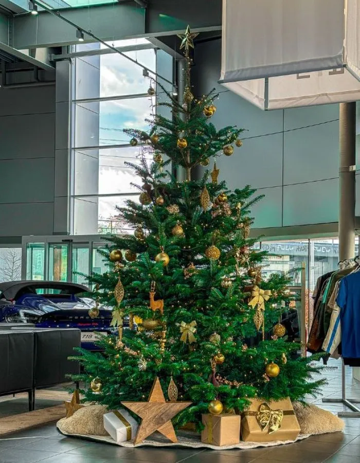 Geschmückter Weihnachtsbaum im Porsche-Autohaus mit goldenen Akzenten