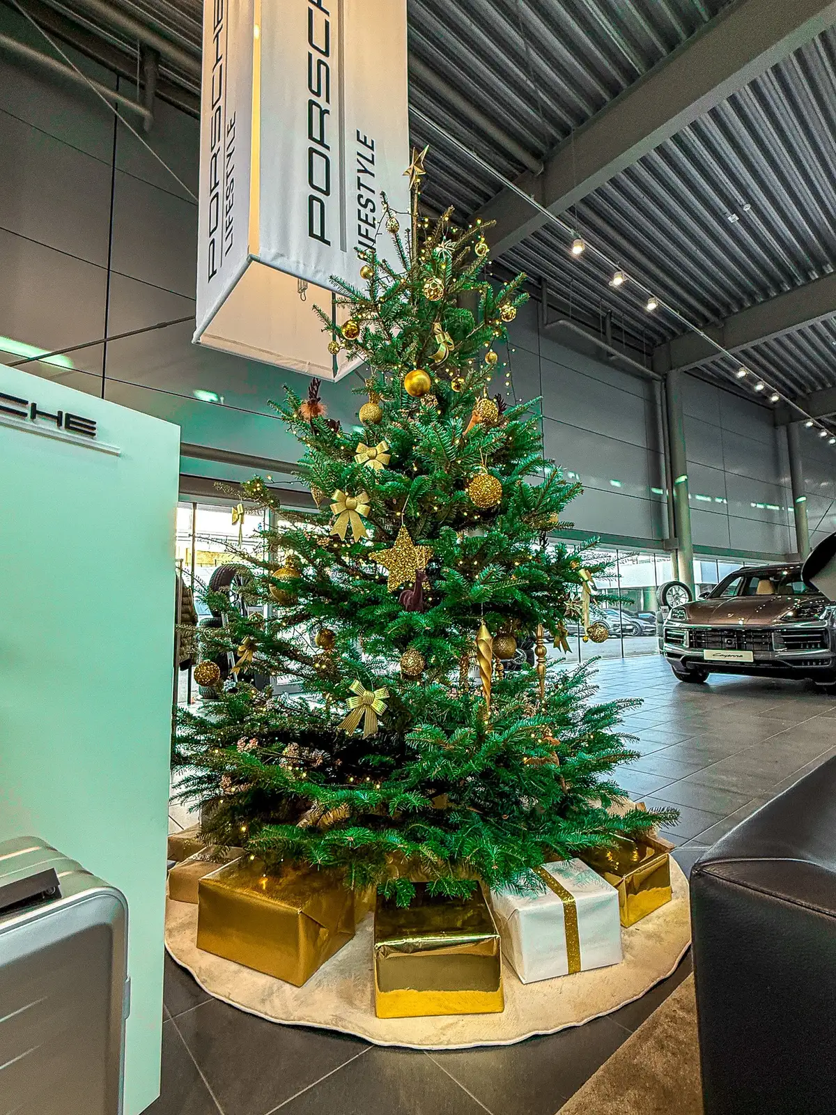 Gold geschmückter Weihnachtsbaum mit Geschenkpaketen im Porsche-Zentrum