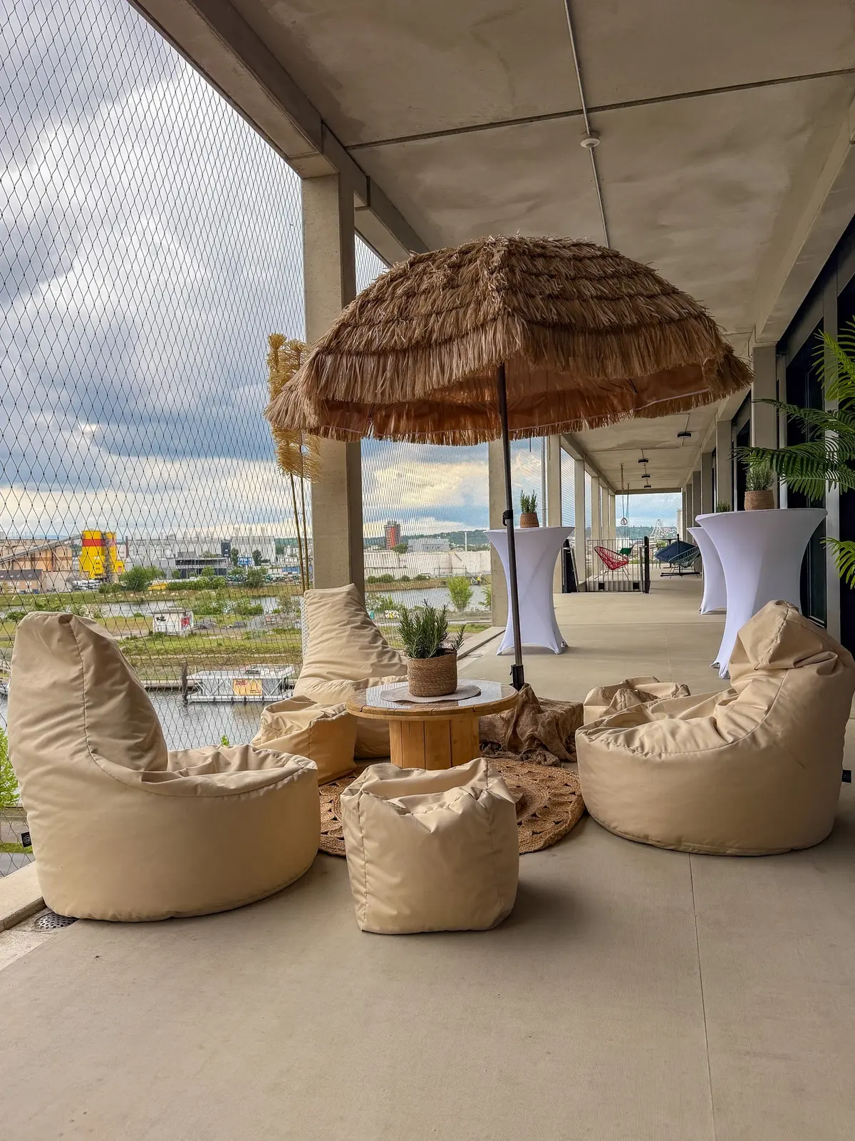 Sommerlounge für TMS mit hellen Sitzsäcken, Pflanzen und einem Strohschirm